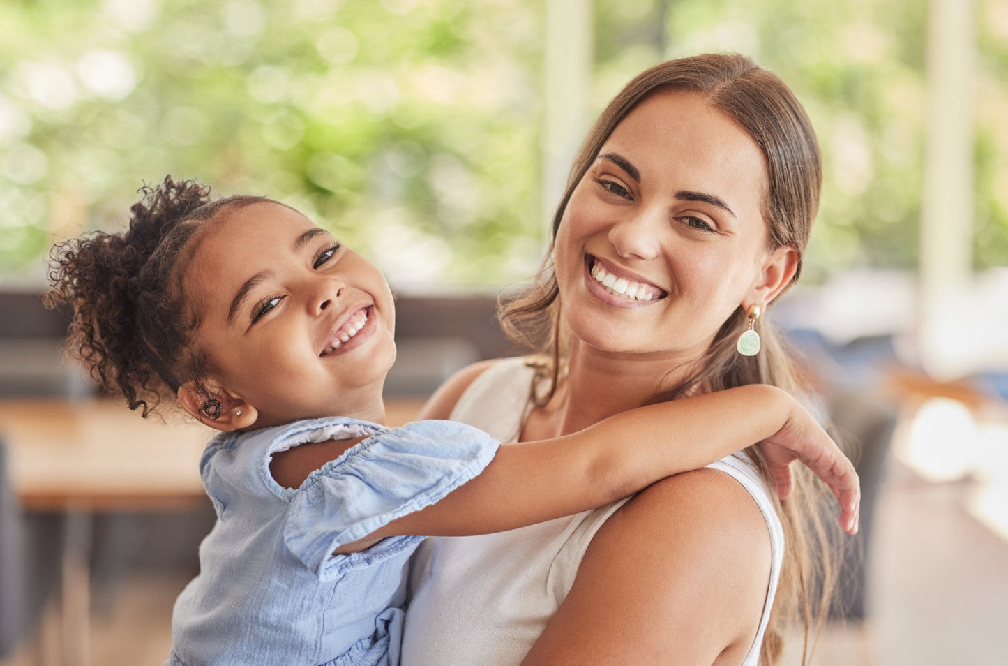 Woman holding a young girl in an indoor setting with blurred background