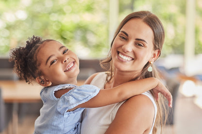 Woman holding a young girl in an indoor setting with blurred background